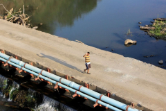 A-student-of-Ba-waves-from-the-temporary-bridge-that-was-built-after-the-floods-washed-away-the-old-bridge
